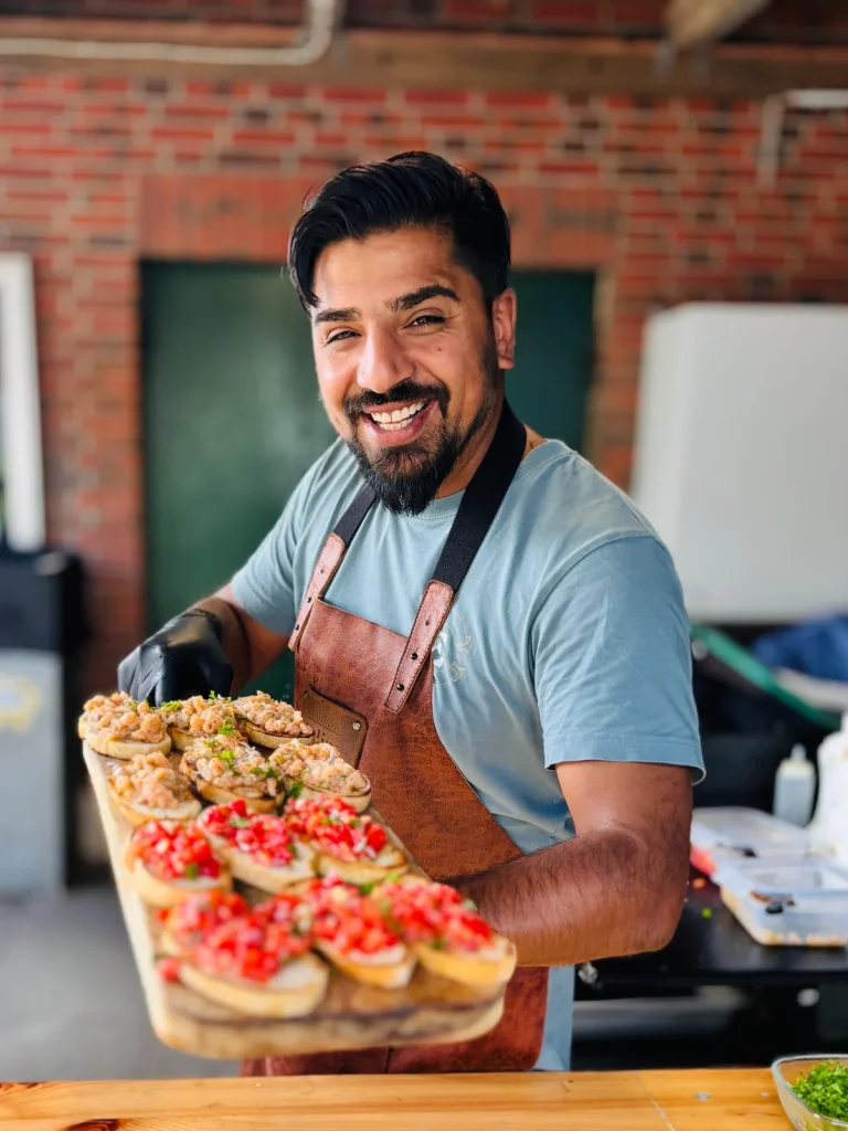 Edip präsentiert ein Holzbrett mit frischen Bruschetta
