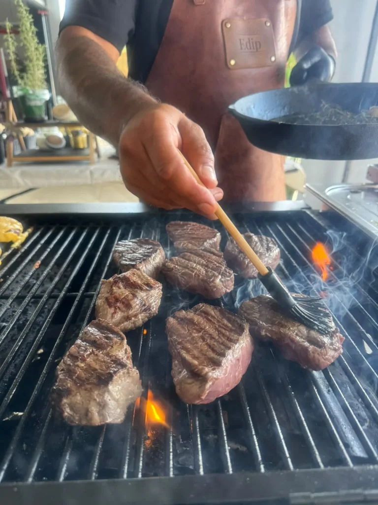 Steaks werden auf dem Grill mit Kräutern bestrichen
